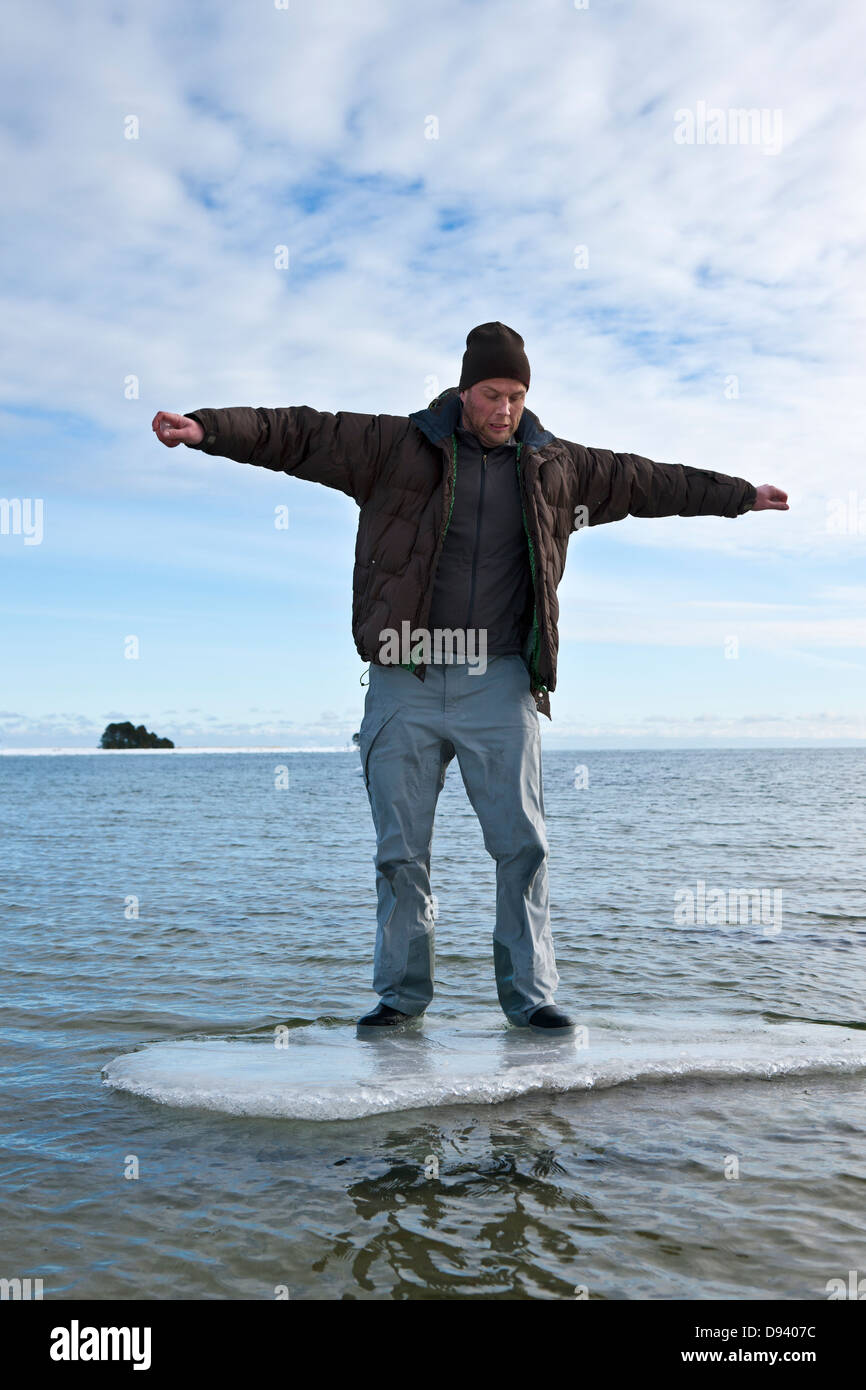 Giovane uomo in piedi sul ghiaccio floe in mare Foto Stock