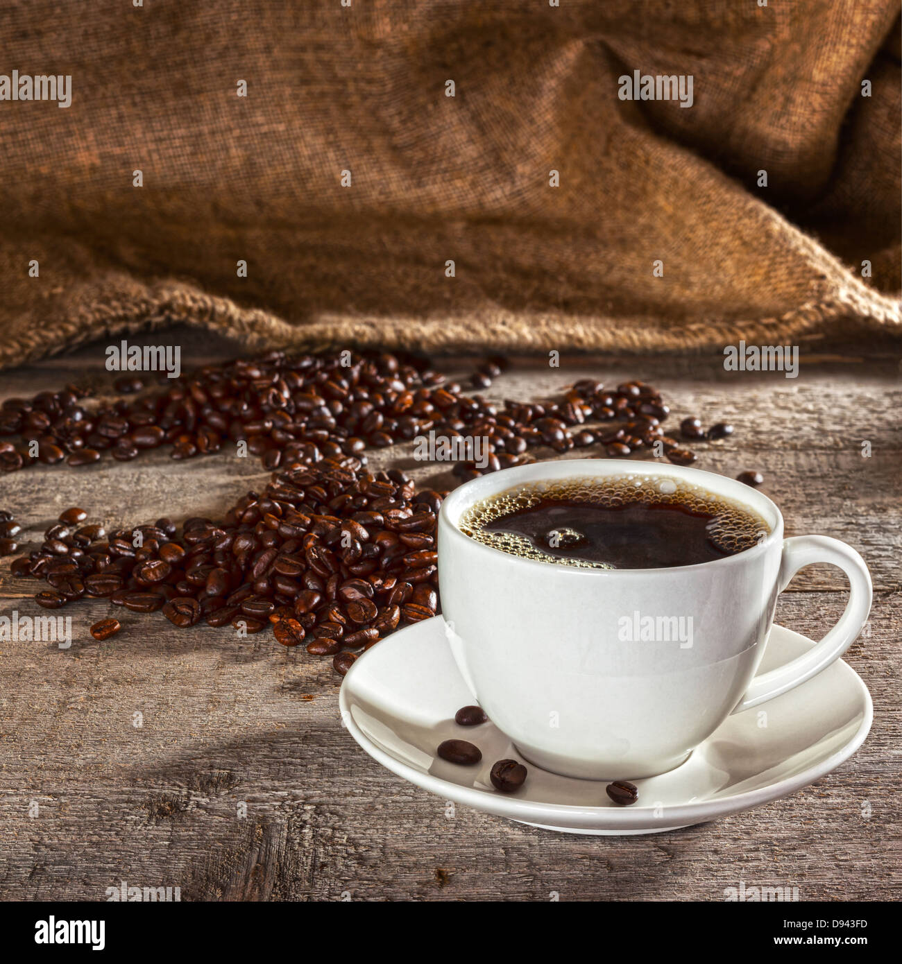 Caffè e sfondo rustico - tazza da caffè con piattino riempito con caffè espresso, con i chicchi di caffè e tela sacco dietro, Foto Stock