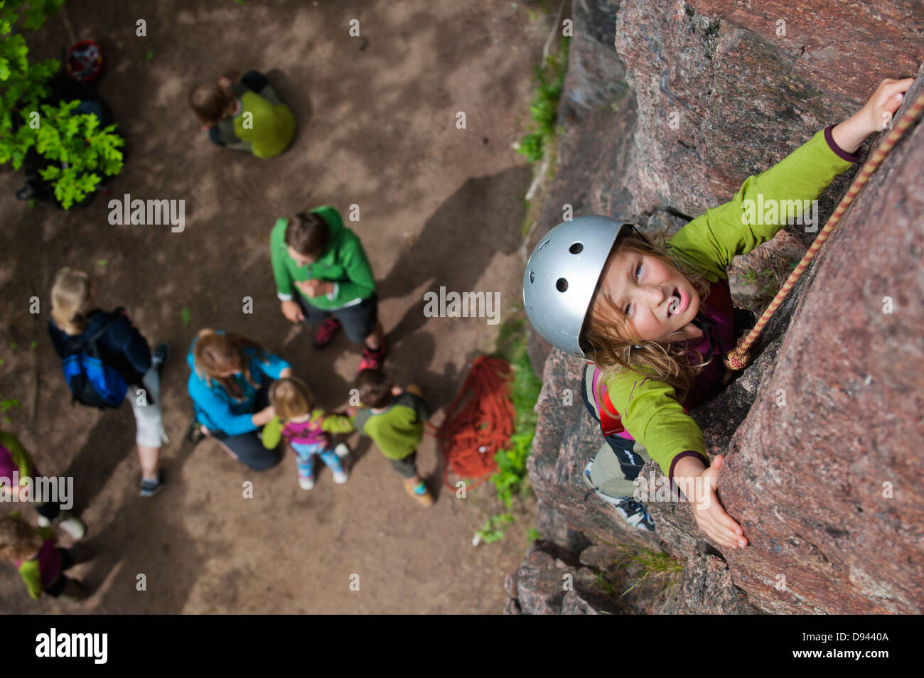 Ragazza arrampicata su roccia con persone sullo sfondo Foto Stock