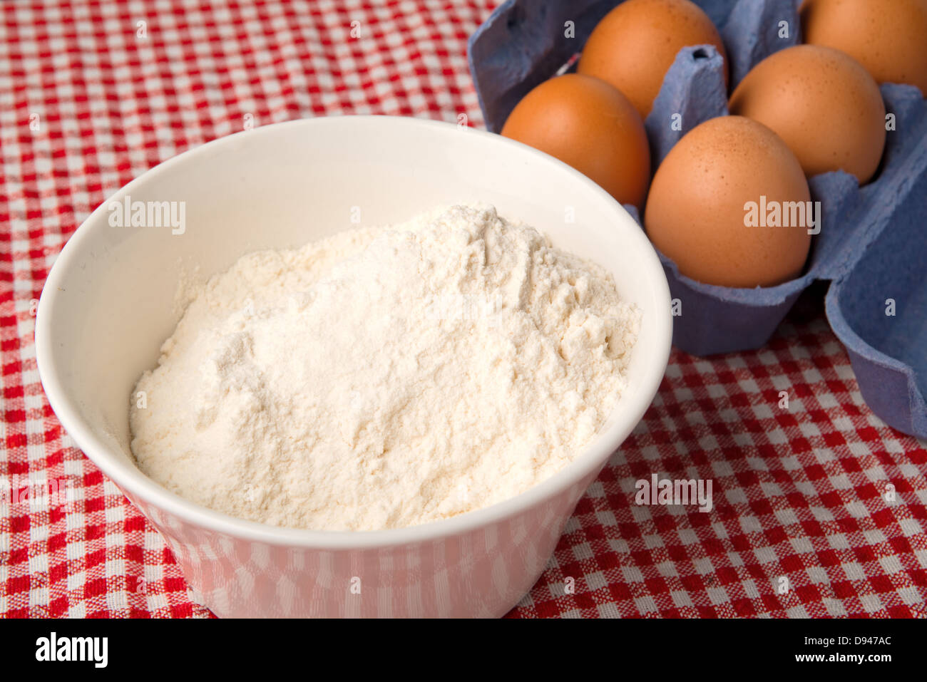 Farina e uova sul tavolo da cucina, crudo ingredienti alimentari. Foto Stock