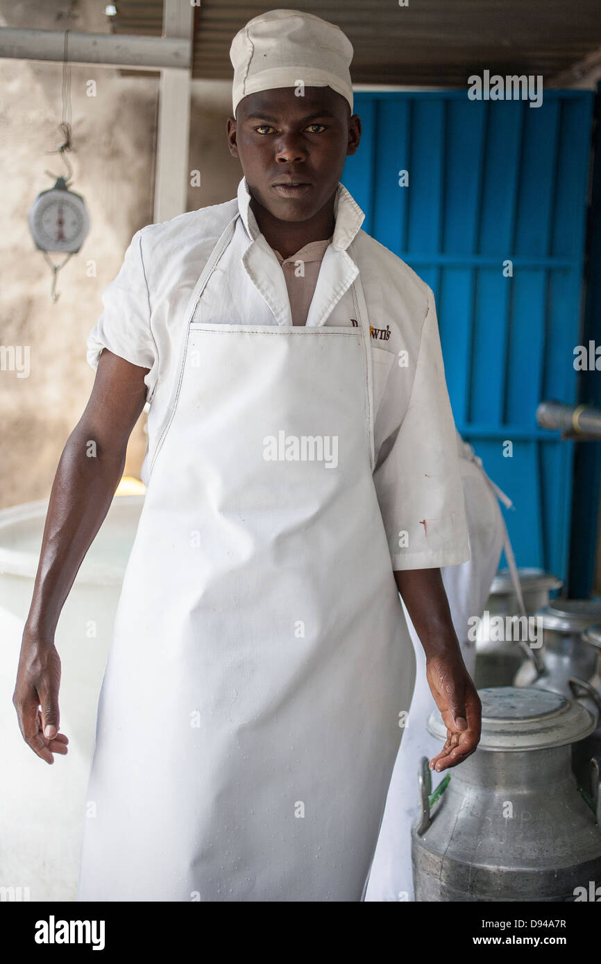 Due uomini in movimento lattine di latte per fare il formaggio su una fattoria di formaggio in Kenya Foto Stock