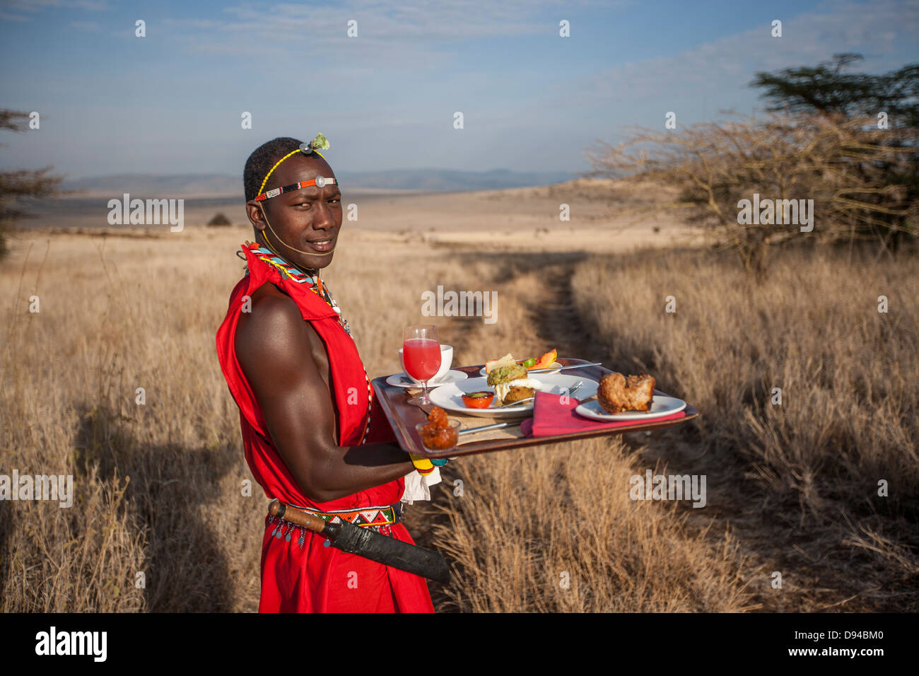 Maasai tribesman offrendo la colazione Foto Stock