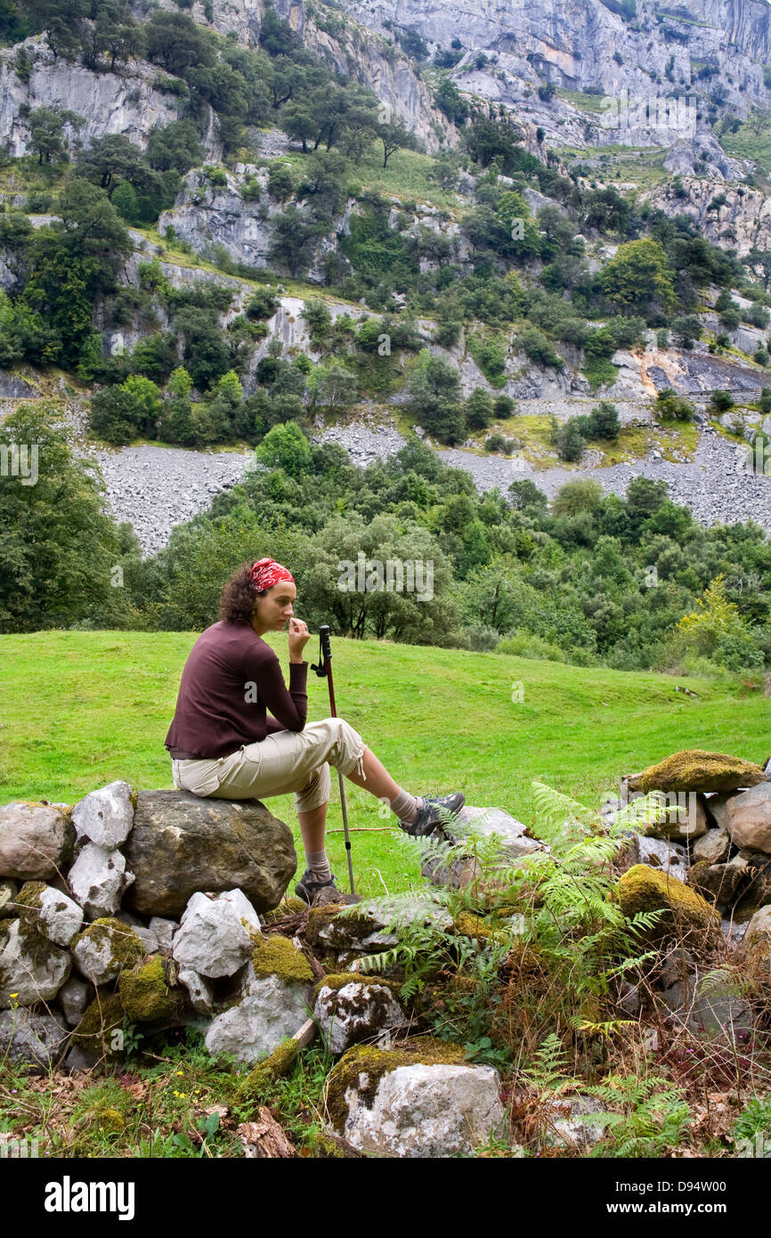 Giovane donna di sedersi su un muro di pietra nel paese. Valle di motivo. Cantabria, Spagna, Europa. Foto Stock