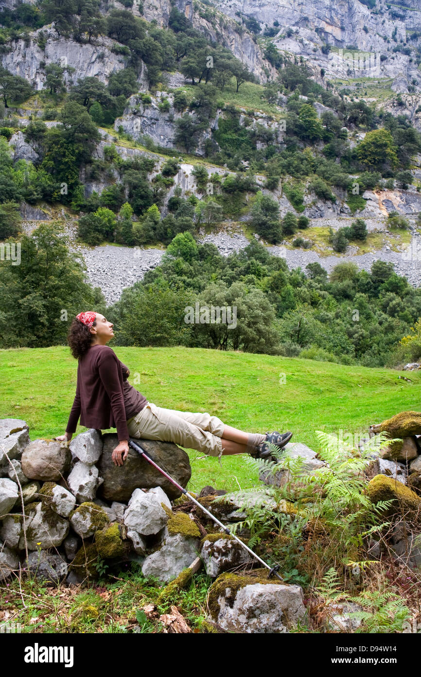 Giovane donna di sedersi su un muro di pietra nel paese. Valle di motivo. Cantabria, Spagna, Europa. Foto Stock