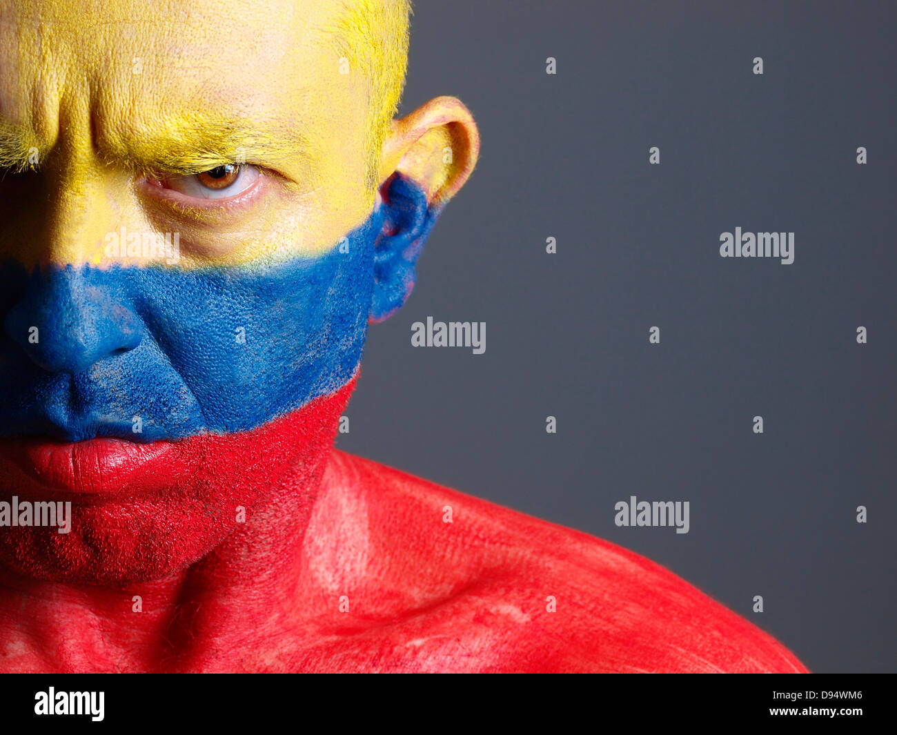 L uomo e il suo volto dipinto con la bandiera della Colombia. L'uomo è grave e composizione fotografica lascia solo metà della faccia Foto Stock