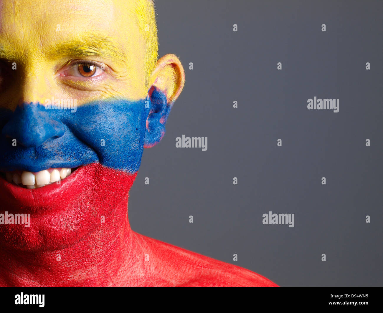 L'uomo faccia dipinta con bandiera colombiana. L'uomo è sempre sorridente e composizione fotografica lascia solo metà della faccia. Foto Stock