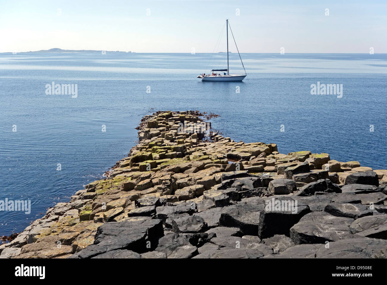 Una barca a vela è ancorato all'estremità sud dell'isola a Staffa nelle Ebridi Interne di Scozia Foto Stock