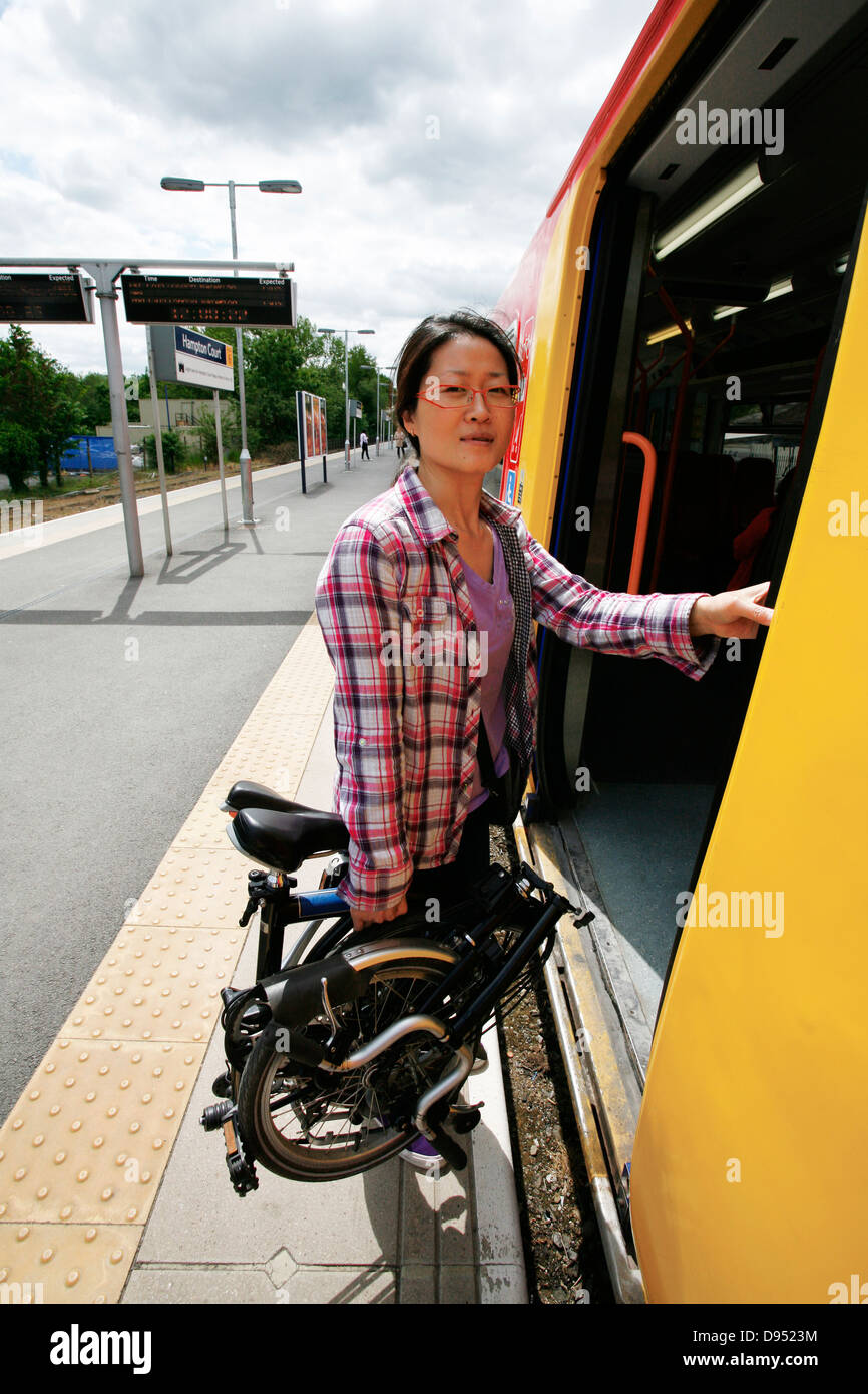 Oriente donna asiatica che porta una bicicletta pieghevole a salire su un treno. Foto Stock