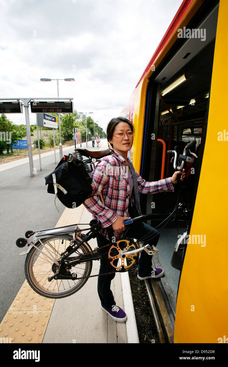 Oriente donna asiatica che porta una bicicletta pieghevole a salire su un treno. Foto Stock