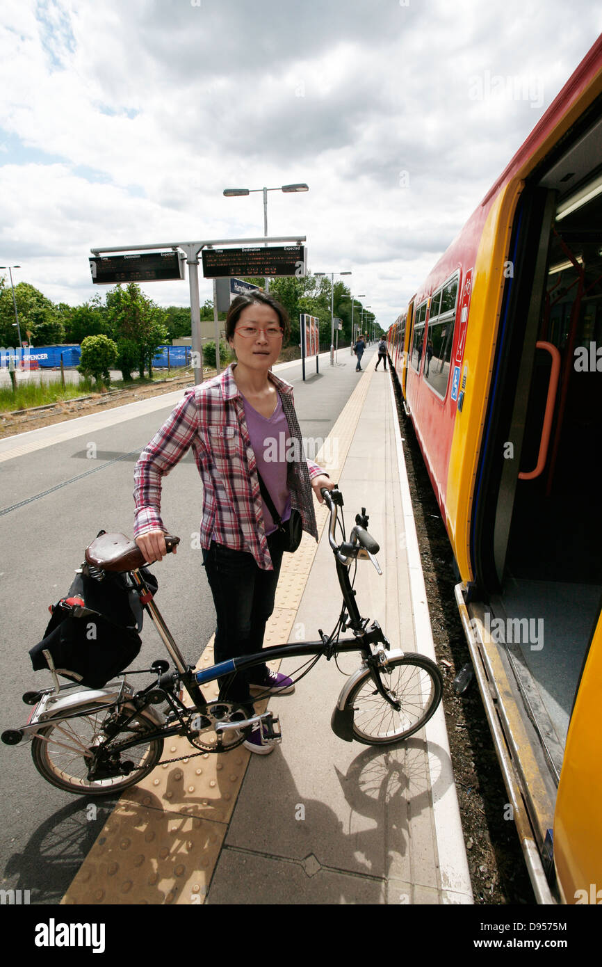 Oriente donna asiatica che porta una bicicletta pieghevole a salire su un treno. Foto Stock