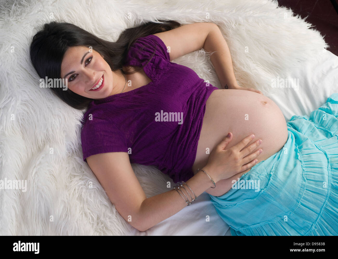 La donna in attesa di un bambino si allunga sul letto per rilassarsi Foto Stock