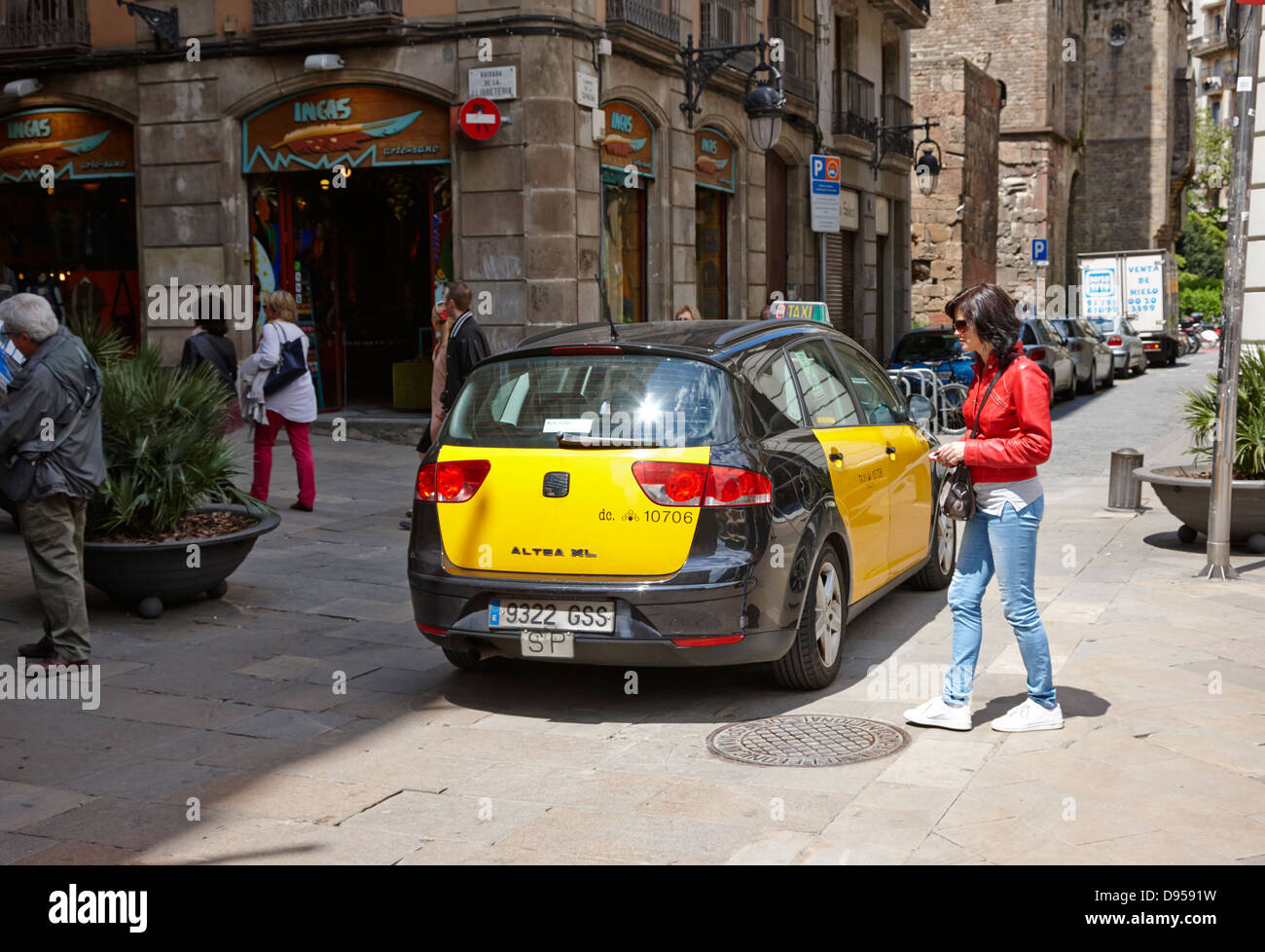 Nero e giallo taxi guida attraverso le strette stradine della città vecchia nel centro della città di Barcellona Catalonia Spagna Foto Stock