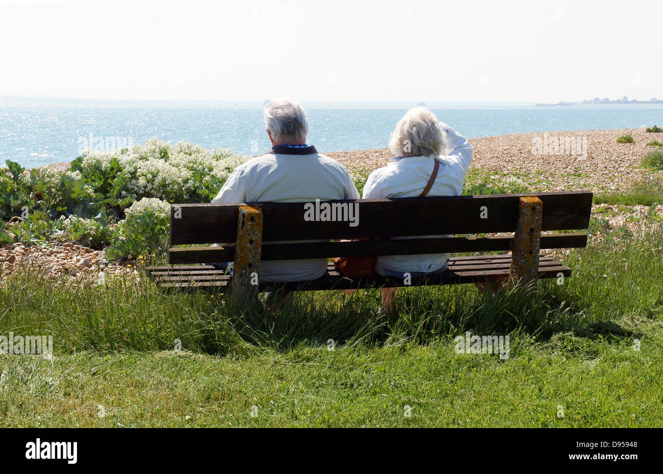 Coppia senior sul banco di lavoro che guarda al mare, Il Solent a Hayling Island Foto Stock