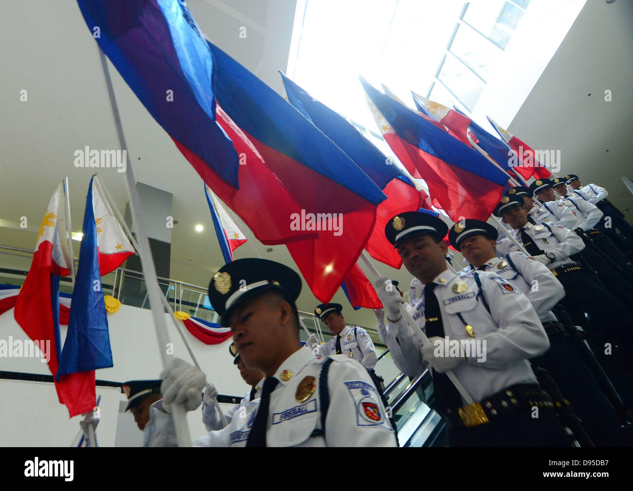 Davao City, nelle Filippine Sud. 12 Giugno, 2013. Filippino guardie di sicurezza mostrato come essi portano Philippine bandiere nazionali per contrassegnare il 115º anniversario dell indipendenza filippina all interno di un centro commerciale a Davao City, nel Sud delle Filippine, 12 giugno 2013. Una sfilata di 115 Philippine bandiere portato dal filippino guardie di sicurezza all'interno di un centro commerciale realizzato parte del 115celebrazioni del giorno dell'indipendenza delle Filippine. Foto Stock