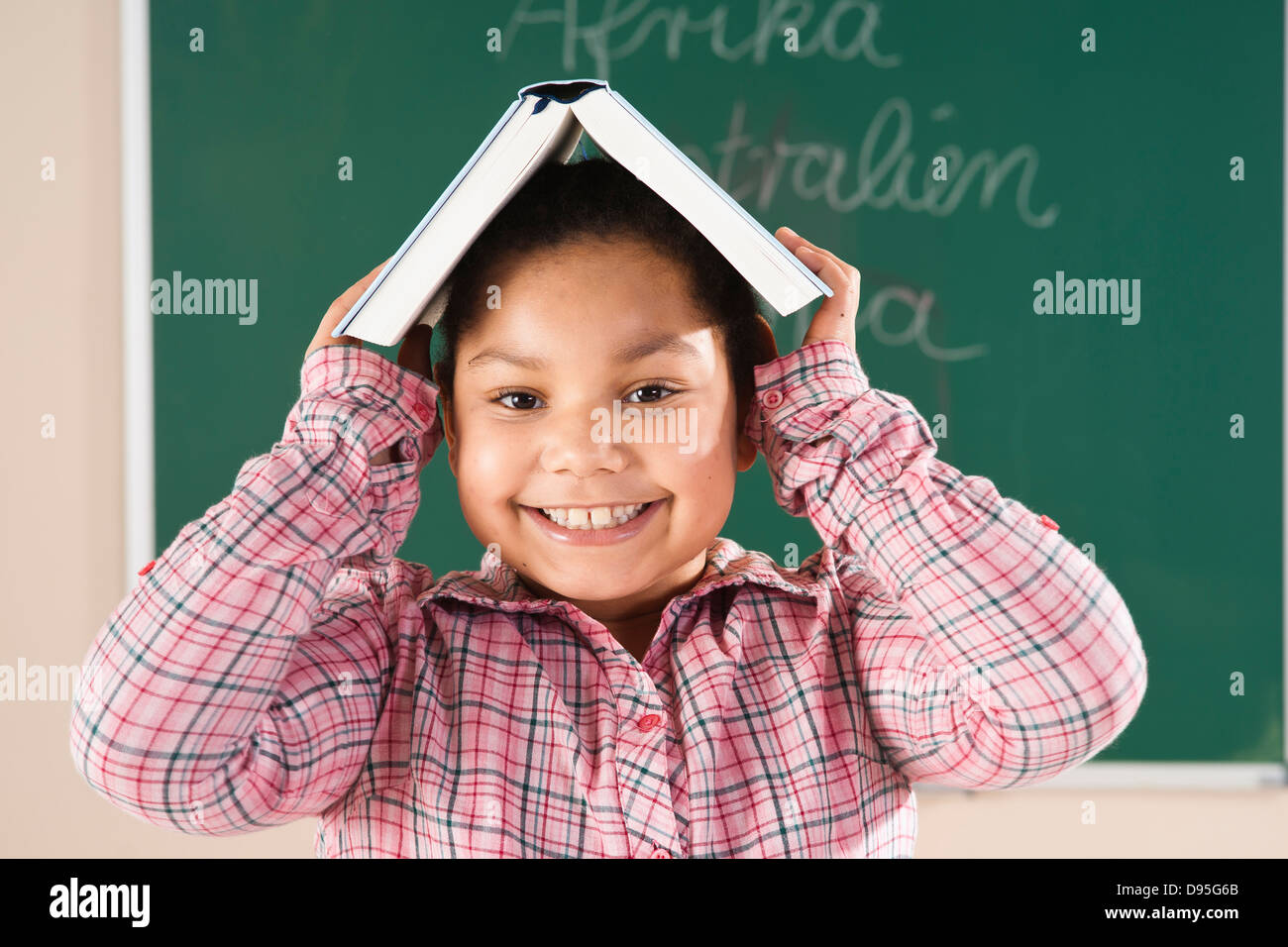 Ragazza con un libro di testo sulla sua testa in Aula, Baden-Württemberg, Germania Foto Stock