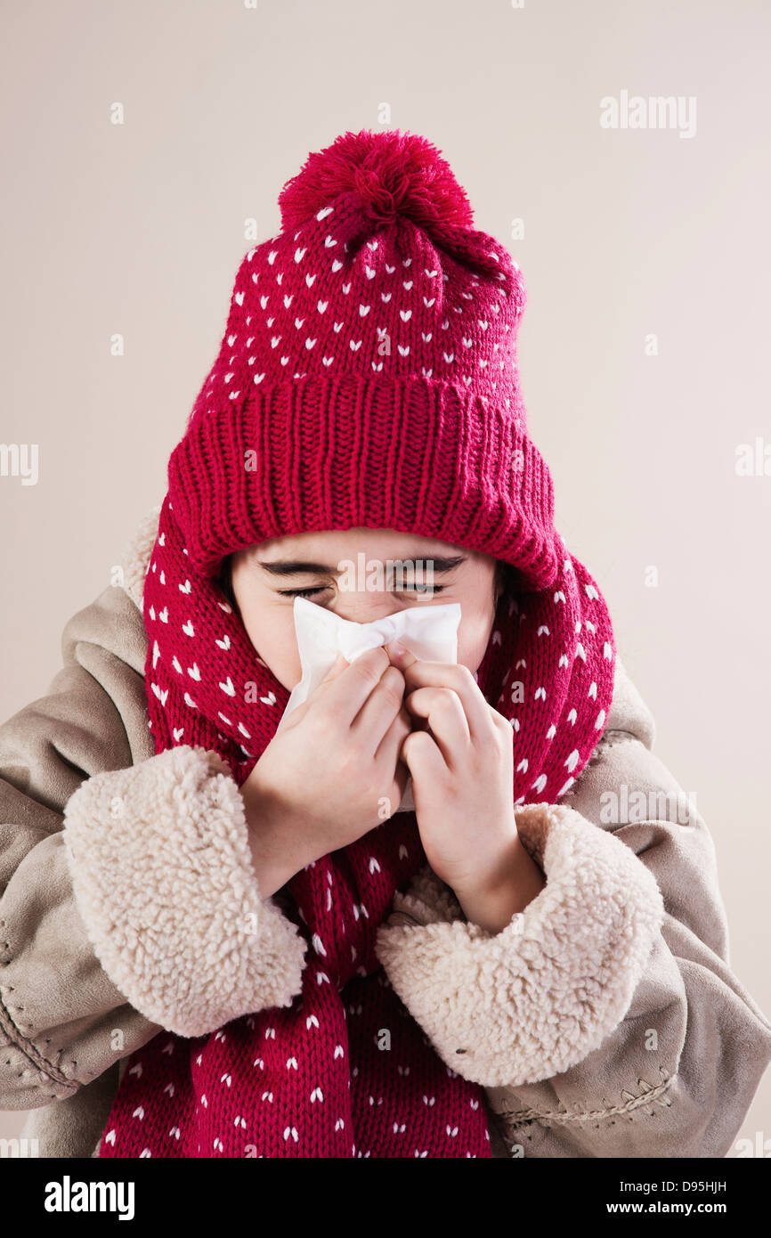 Portraif della ragazza che indossa un cappello e sciarpa soffia il naso in Studio Foto Stock