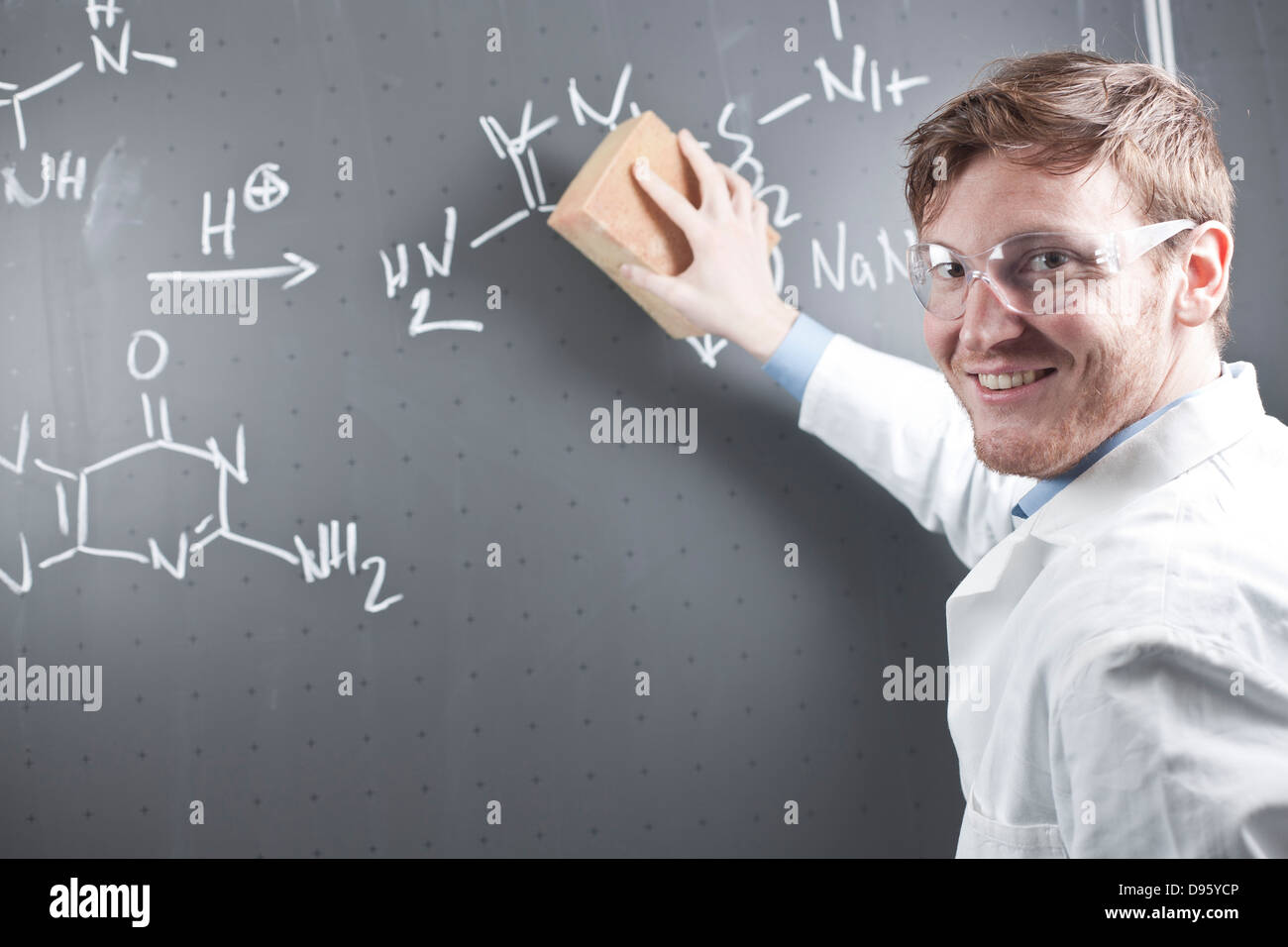 Germania, giovane scienziato cancellazione equazione chimica su chalk board Foto Stock