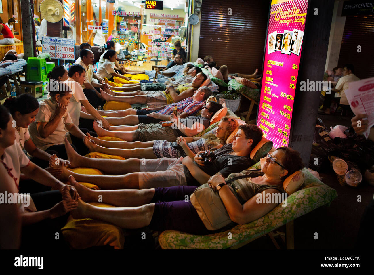 I turisti e i locali sdraiarsi in righe per il tradizionale massaggio Tailandese dei piedi in Khao San Road Foto Stock