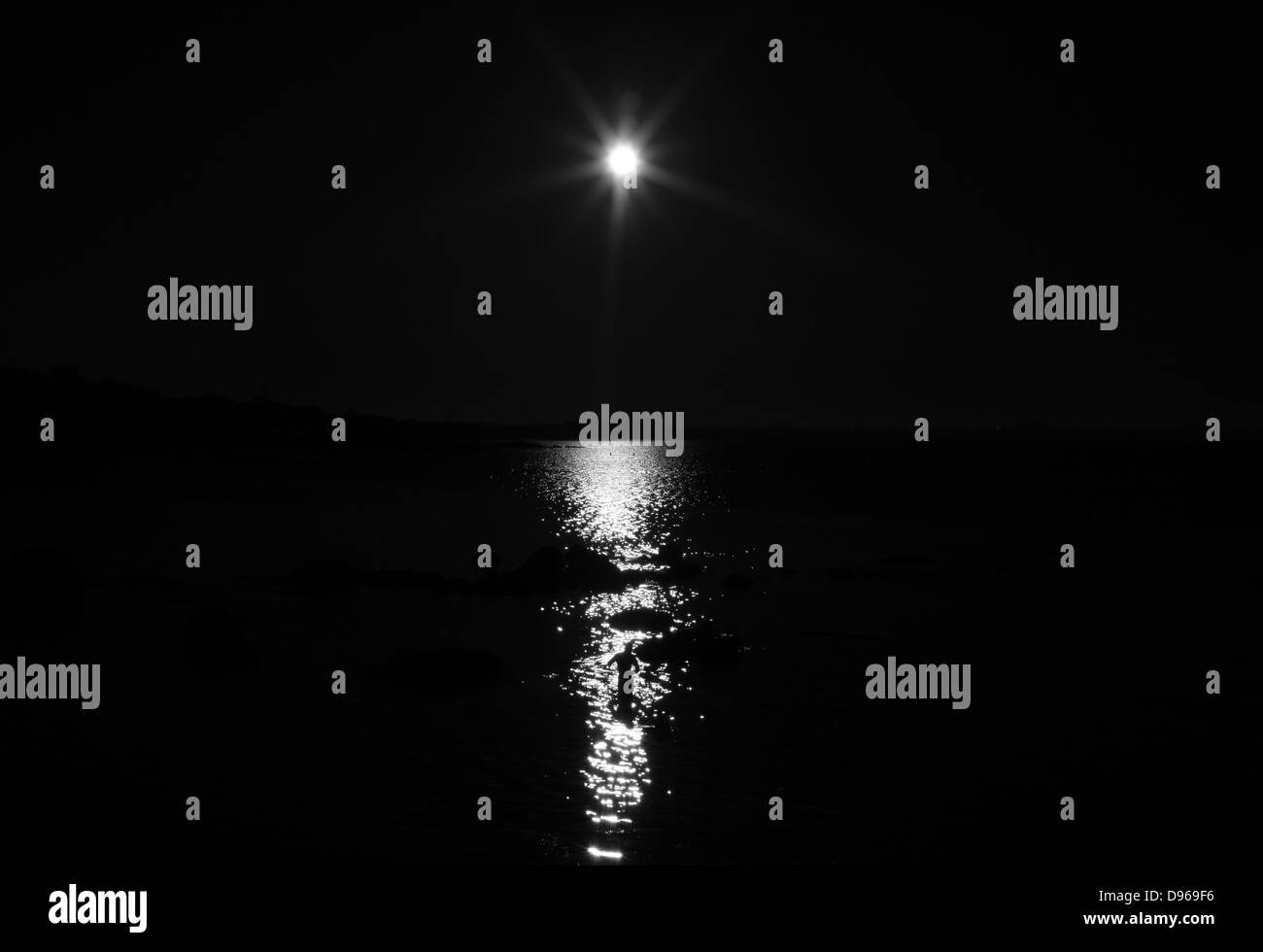 La figura di un uomo in mare profilarsi da un sole luminoso. Foto Stock