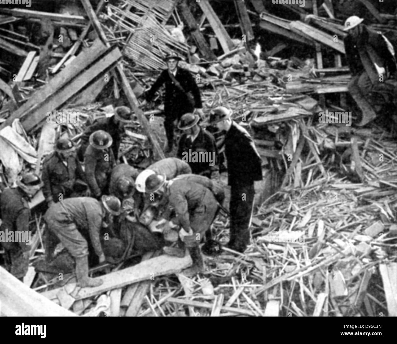Gli operatori di soccorso rilasciando ferito dalle macerie di un edificio distrutto dai bombardamenti tedeschi: 1940. La seconda guerra mondiale. Foto Stock