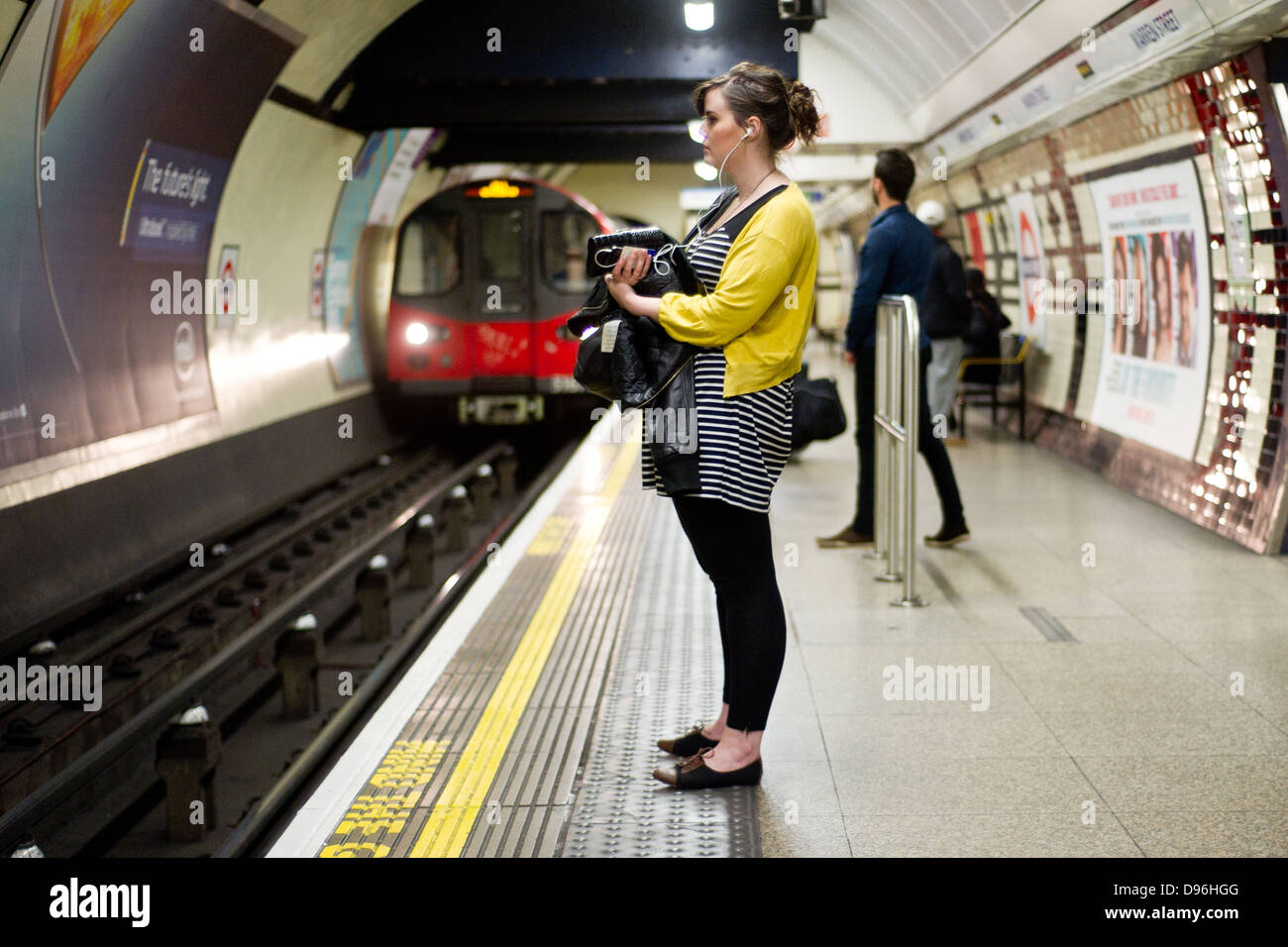 Una donna attende a Londra della metropolitana treno sulla piattaforma di Warren Street station. Foto Stock