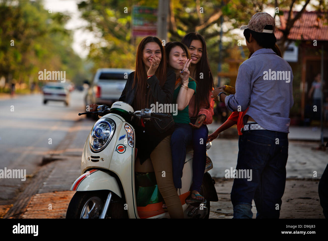 3 ragazze su uno scooter, Siem Reap Cambogia, rendendo il segno di pace Foto Stock