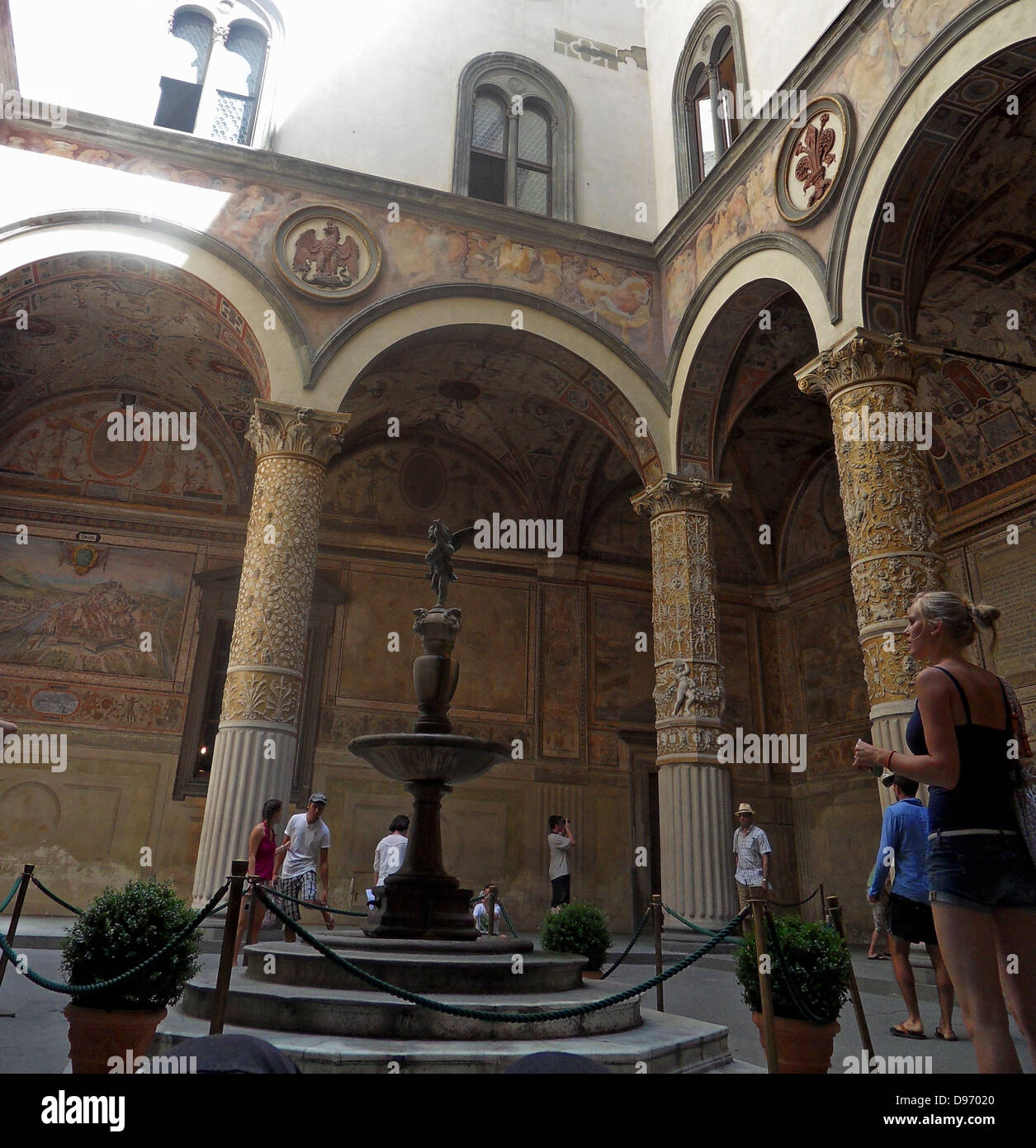 Il Palazzo Vecchio, Firenze, Italia. Questa massiccia, romanico. Il primo cortile fu progettato nel 1453 da Michelozzo. Nelle lunette, alta intorno al cortile, sono creste della Chiesa e della città gilde. Al centro la fontana di porfido è di Battista del Tadda. Foto Stock