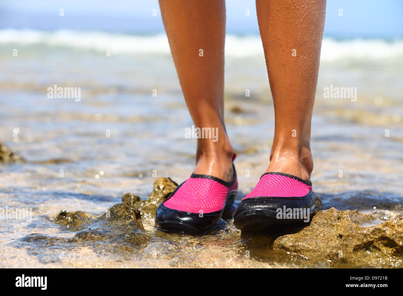 Scarpe da acqua / Nuoto scarpa in neoprene rosa sulle rocce in acqua sulla  spiaggia. Primo piano