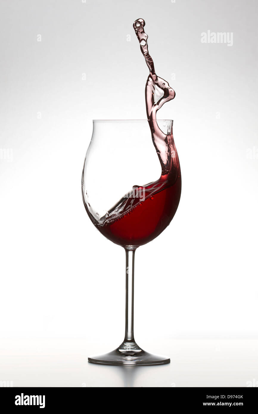 Vino rosso spruzzi in vetro su sfondo bianco Foto Stock