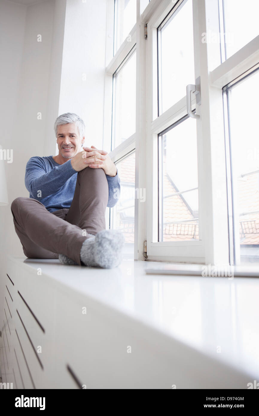 In Germania, in Baviera, Monaco di Baviera, Ritratto di uomo maturo seduto alla finestra, sorridente Foto Stock