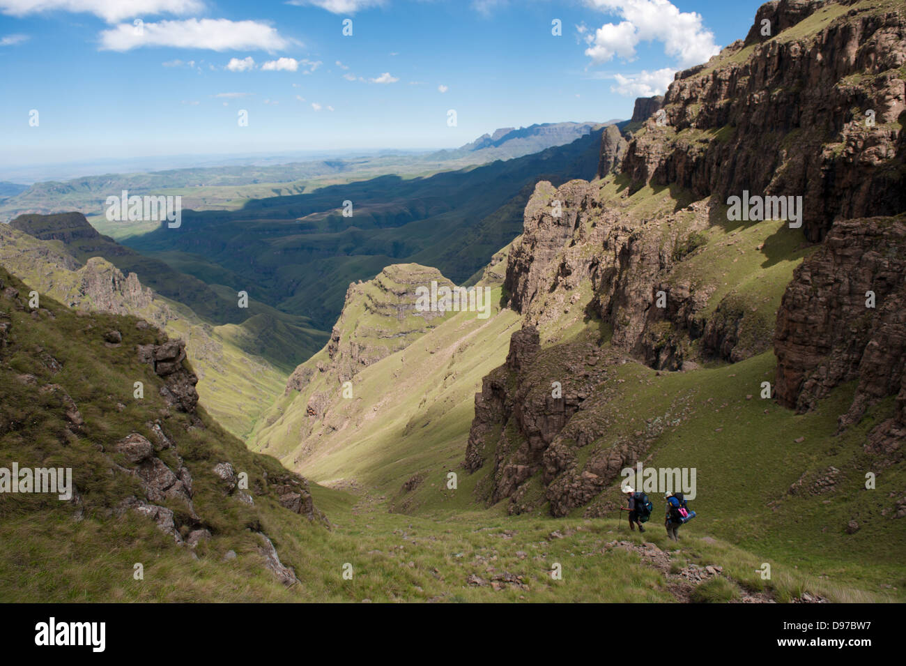 Gli escursionisti decending dalla scarpata a due gemelli Grotta, Ukhahlamba Drakensberg Park, Sud Africa Foto Stock