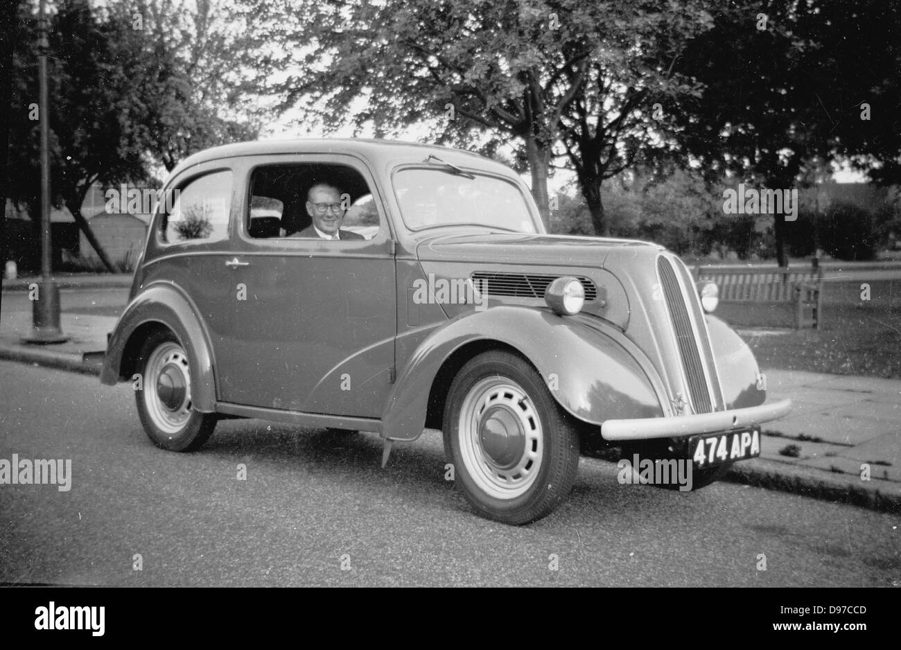 Storico degli anni cinquanta. Un anziano gentiluomo con orgoglio si siede nel sedile del conducente nella sua auto. Foto Stock