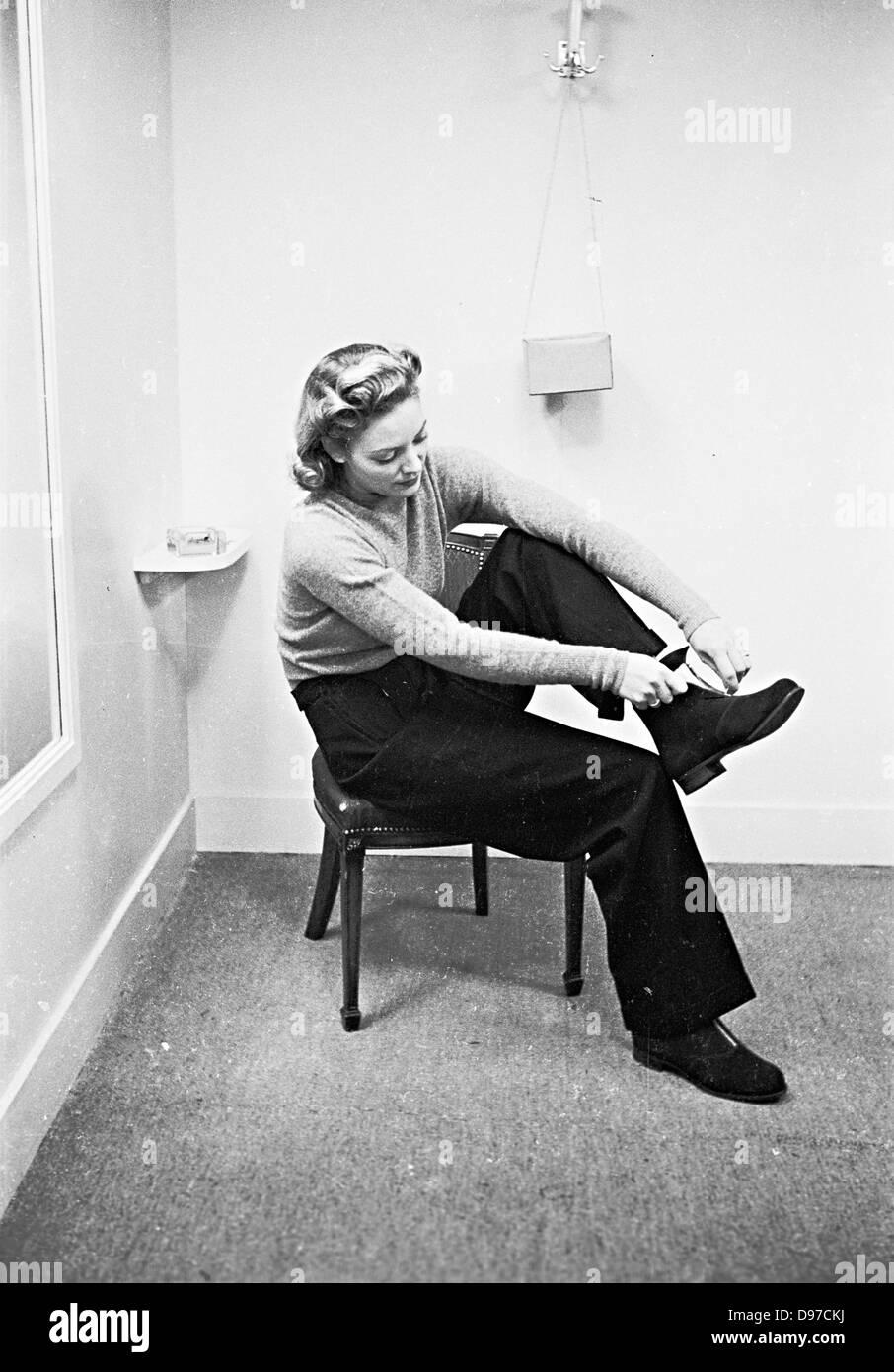Storico, 1940s. Tempo di guerra in Inghilterra. Una signora cerca su un piccolo elegante Stivale camoscio presso i famosi magazzini Harrods, Londra. Foto Stock