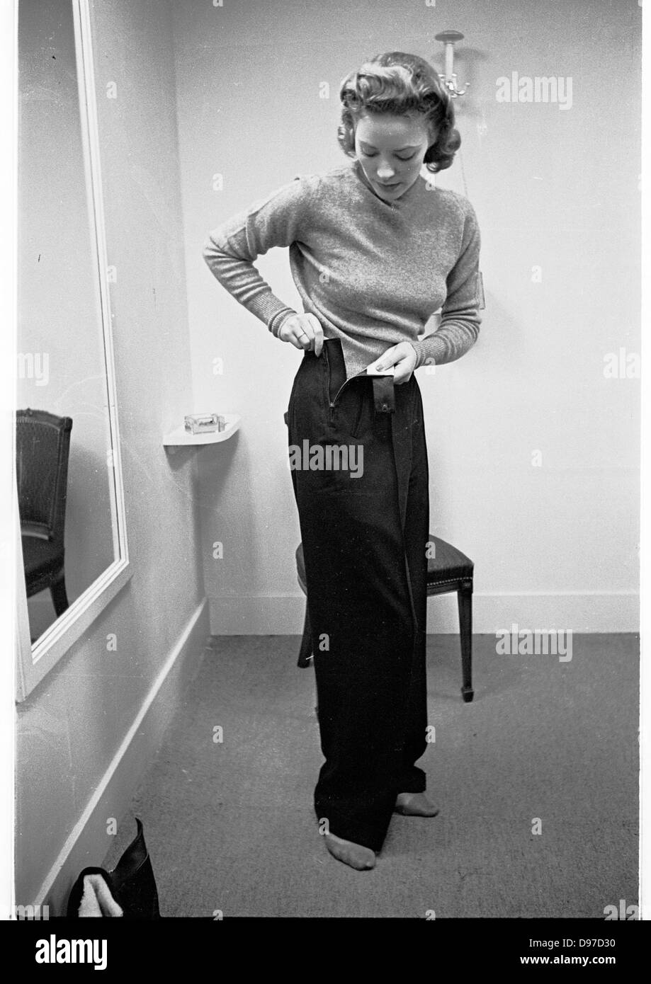 Storico, 1940s. Tempo di guerra in Inghilterra. Una signora tenta in un paio di pantaloni a famosi magazzini Harrods a Londra. Foto Stock