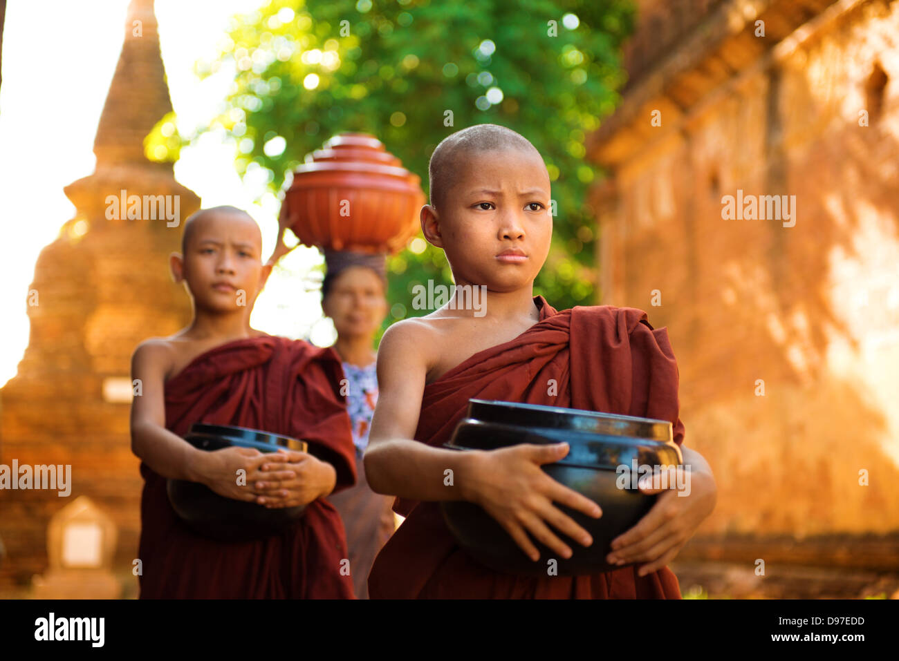 I giovani monaci buddisti di mattina a piedi alms nella vecchia Bagan, Myanmar Foto Stock