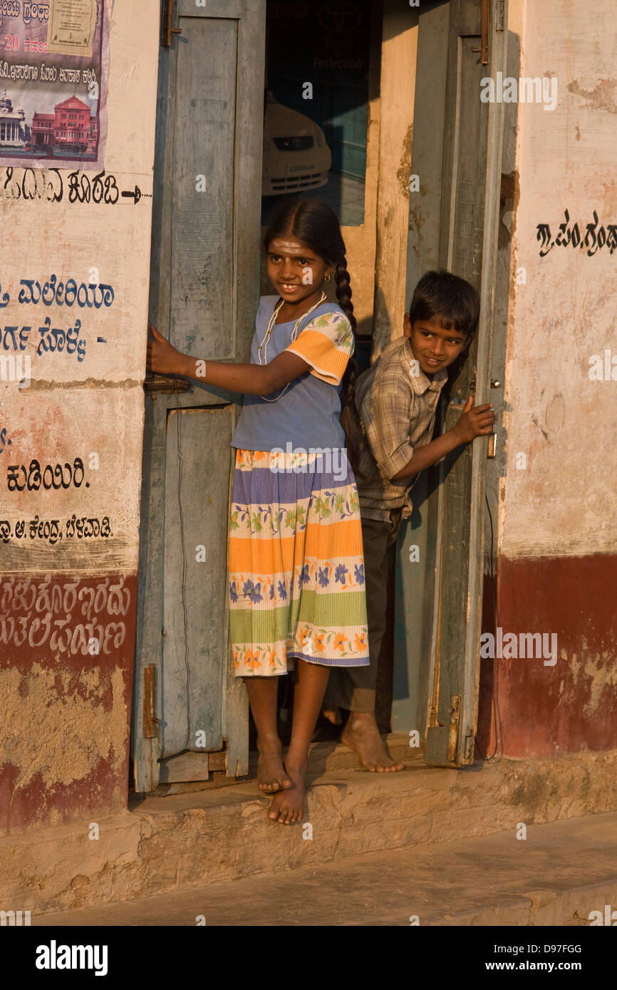 Asia, India, Karnataka, Belavadi, due bambini guardando fuori della porta anteriore Foto Stock