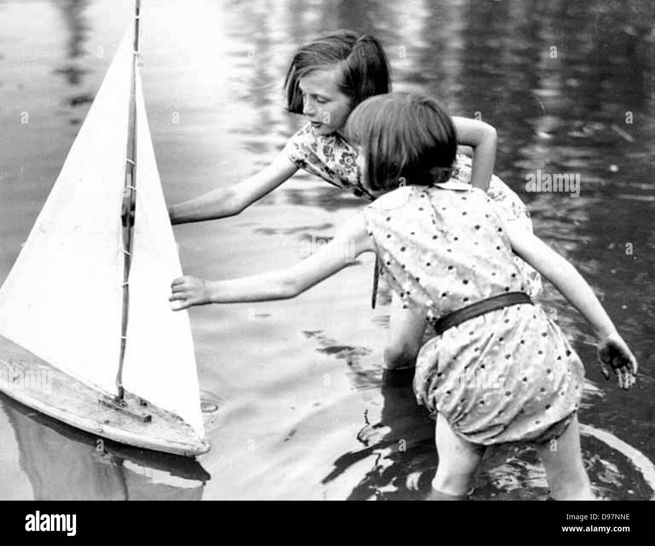 Due ragazze di raggiungere per un giocattolo di barca a vela, Seattle, Washington Foto Stock