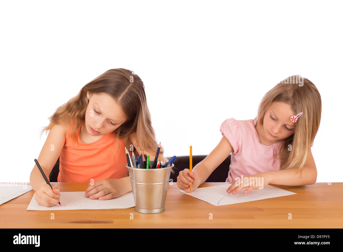 Due bambini di concentrato di disegnare su una tavola di legno. Isolato su uno sfondo bianco. Foto Stock