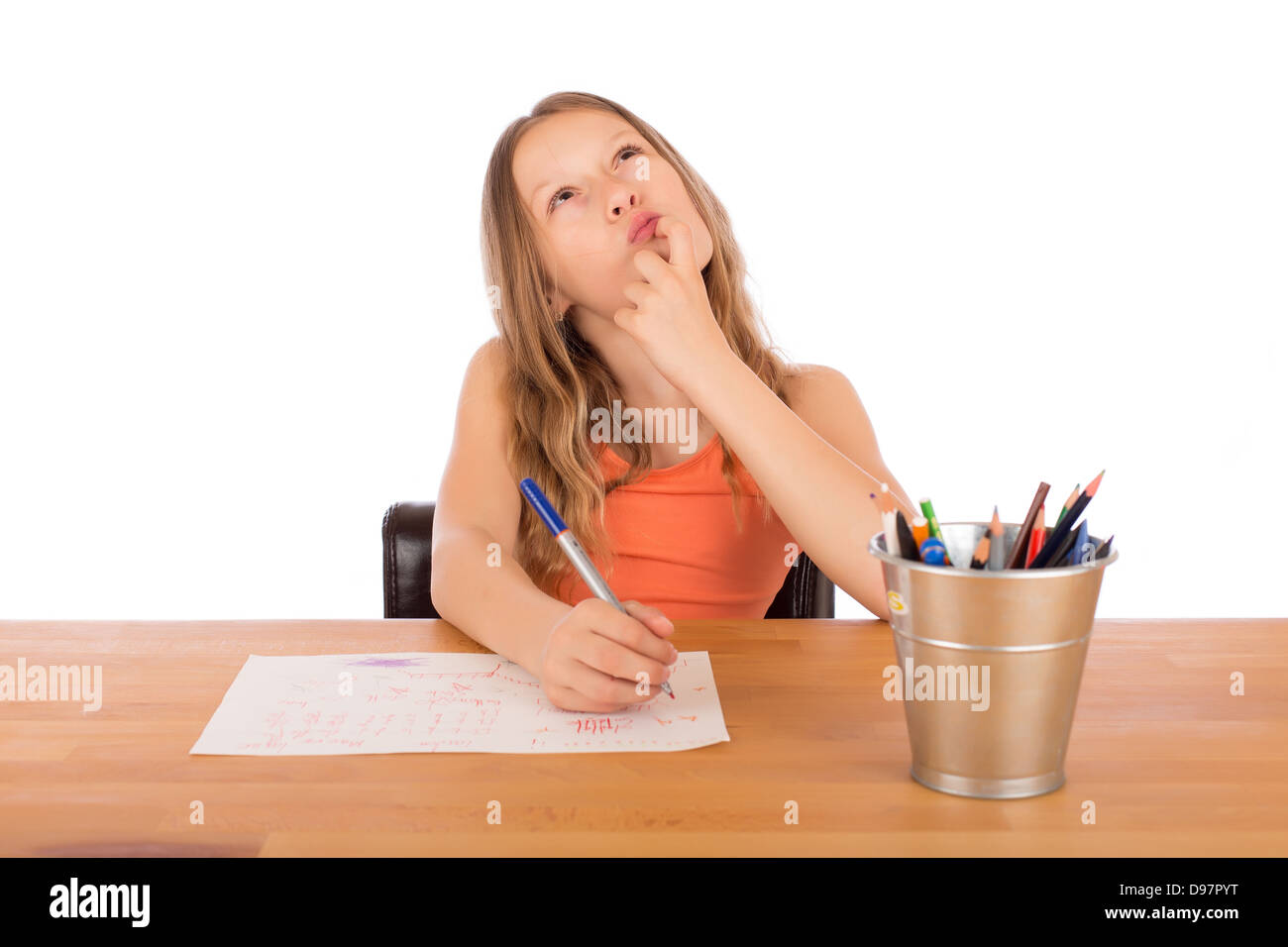 Bambino seduto a un tavolo di legno cercando di realizzare un disegno. Isolato su uno sfondo bianco. Foto Stock