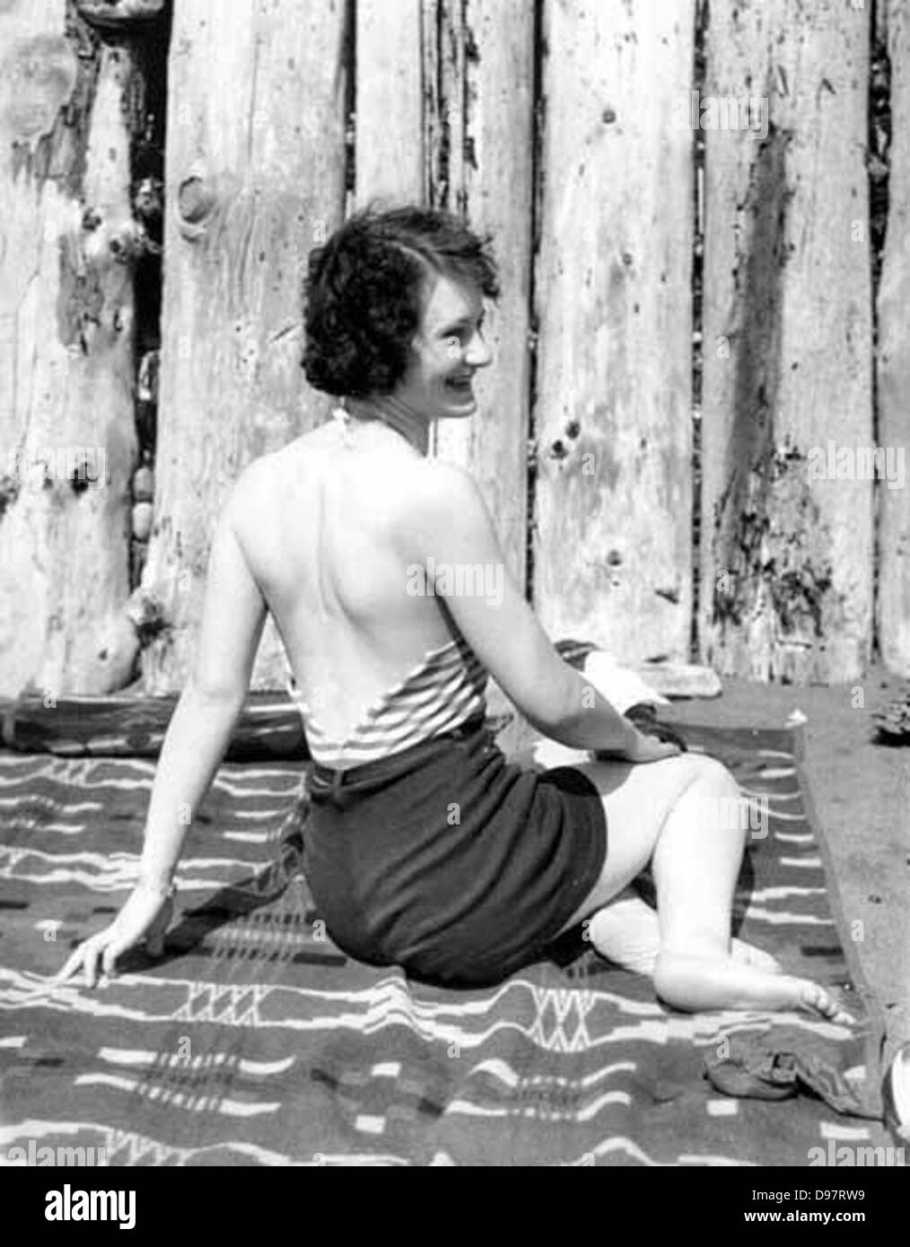 Donna in costume da bagno seduta su una coperta nella parte anteriore di una recinzione di registro, probabilmente stato di Washington Foto Stock