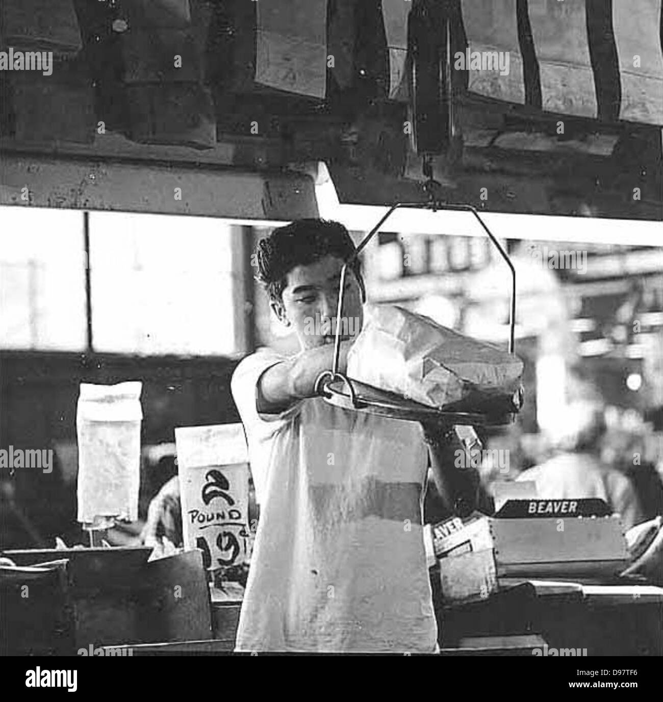 Questa immagine cattura un commerciante che pesa prodotti al Pike Place Market di Seattle. Il mercato, noto per la sua atmosfera vivace e i prodotti freschi, è un punto di riferimento storico a Seattle, Washington. Foto Stock