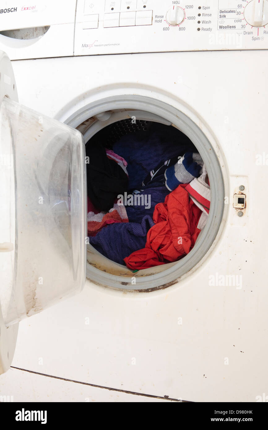 Una macchina di lavaggio, pieno di vestiti, con una porta aperta Foto Stock