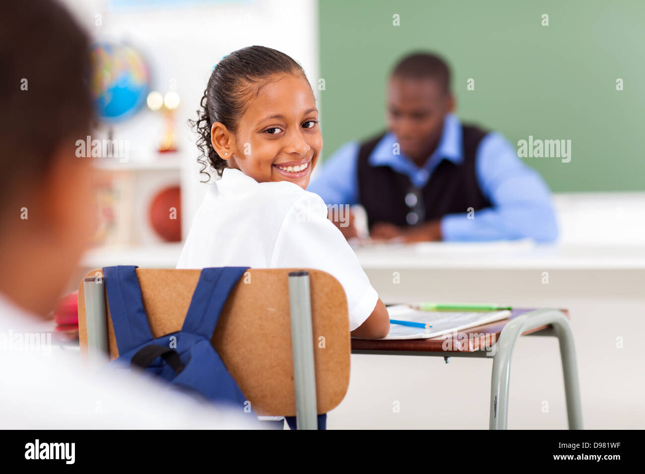 Carino schoolgirl elementari in aula con un compagno di classe e insegnante Foto Stock
