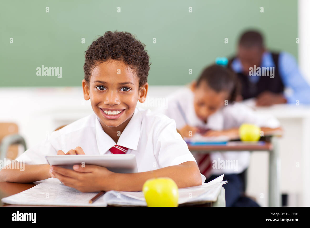 La scuola primaria boy utilizzando computer tablet in aula Foto Stock