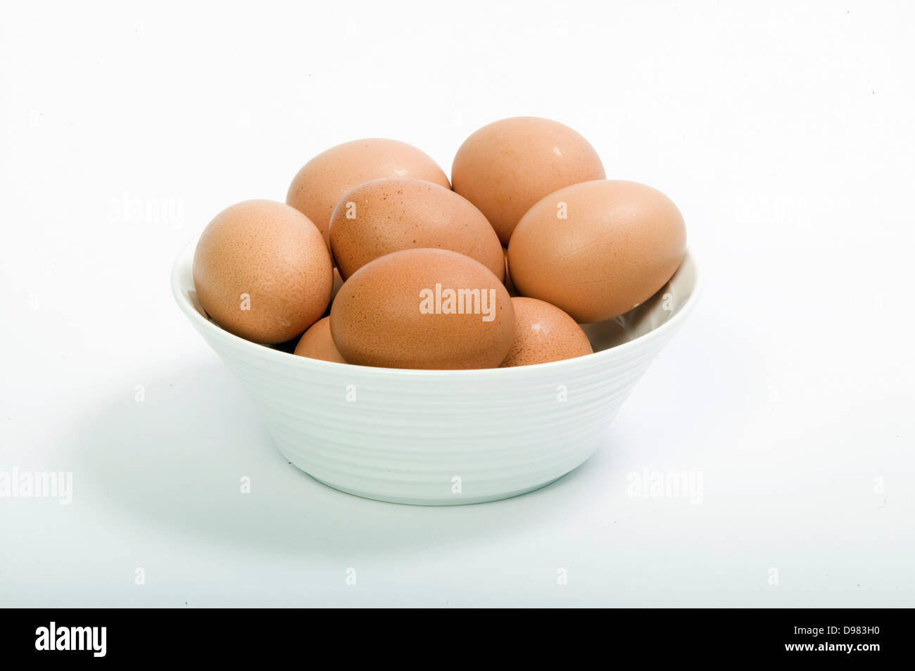 Una ciotola di fresca bruna di gallina uova contro uno sfondo bianco. Foto Stock