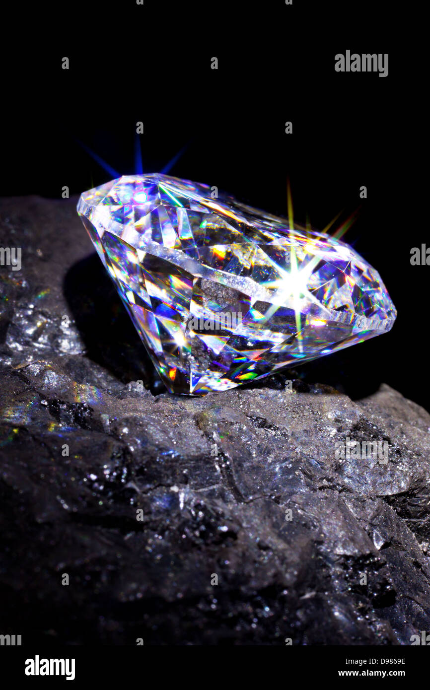 Un unico taglio diamante su un pezzo di carbone per simboleggiare entrambi essendo a base di carbonio, studio shot preso contro uno sfondo nero. Foto Stock