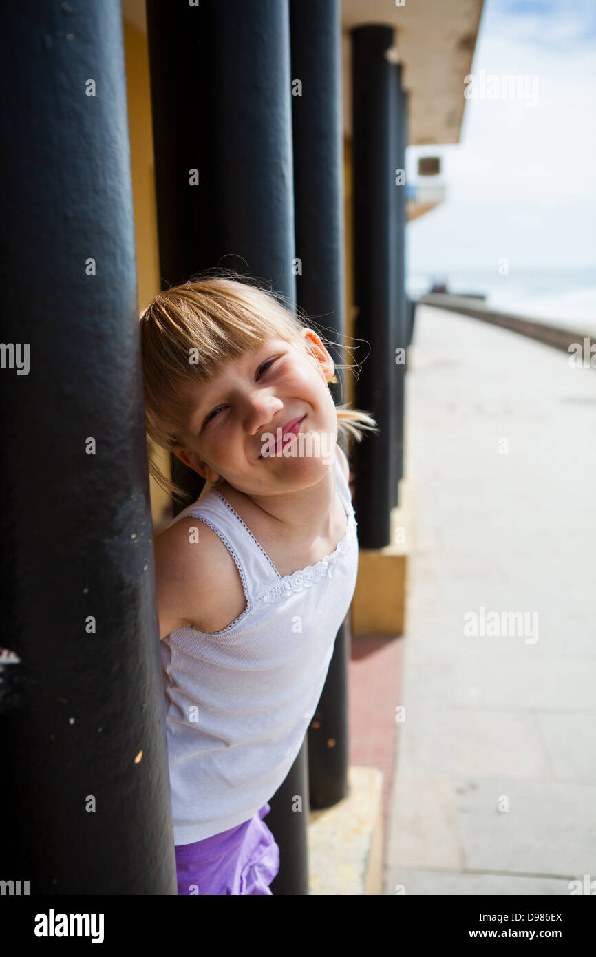 Sorridente ragazza giovane tra montanti strutturali al fianco di passerella sulla spiaggia Foto Stock