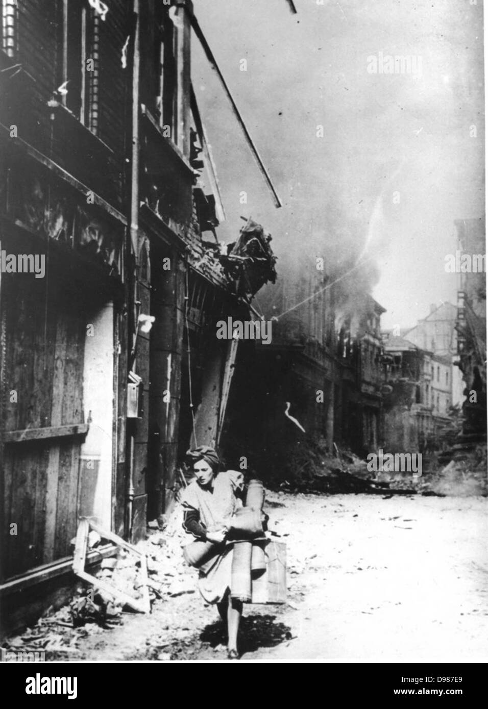 In una città tedesca nel 1945 una donna fugge dopo le esplosioni rock gli edifici. Foto Stock