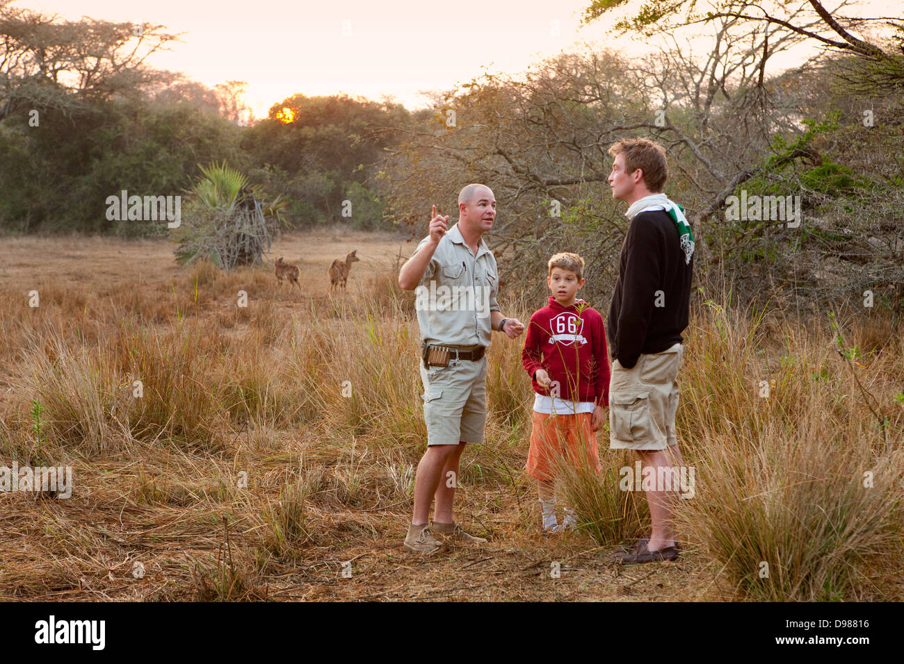 I turisti che studiano le tracce di gioco con Daryl, la loro guida in Phinda Game Reserve, Sud Africa Foto Stock
