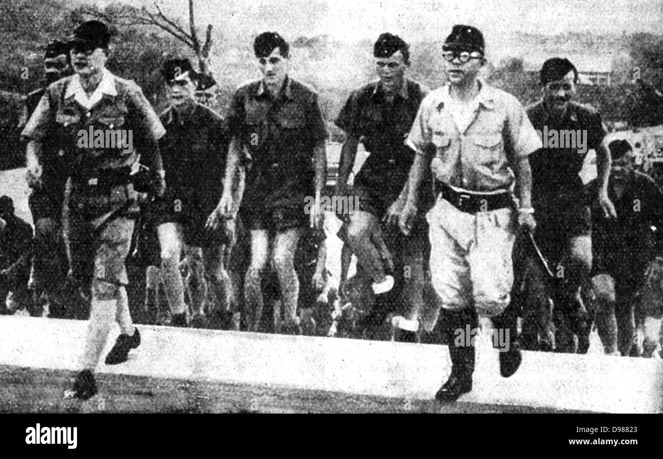 Il nemico di presidio presso la base navale di Singapore, sotto il comando del generale giapponese Yamashita, incluso un certo numero di soldati tedeschi, alcuni dei quali sono qui essendo condotta dai funzionari giapponesi su un giro panoramico della zona. Foto Stock
